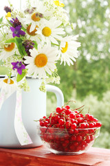 A bouquet of wildflowers and a glass bowl of red currant