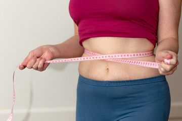 Closeup of woman pinching belly fat. Young slim woman in blue shorts pinching her abdomen. Diet and...