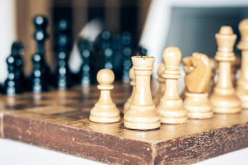 Old well used wooden chess pieces on a chessboard, retro leadership concept on white background.