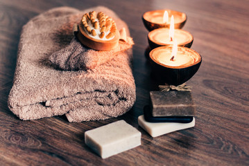Obraz na płótnie Canvas Burning spa aroma candles in coconut shell, handmade soap, towel and washcloth, spa concept background.