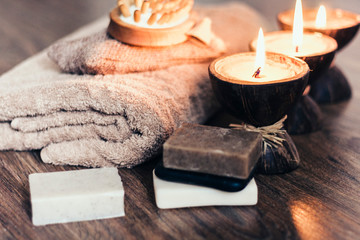 Fototapeta na wymiar Burning spa aroma candles in coconut shell, handmade soap, towel and washcloth, spa concept background.