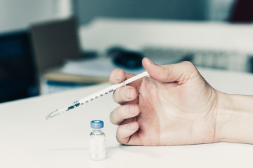 female hand with a medical syringe and bottle with insulin for diabetes on white table.
