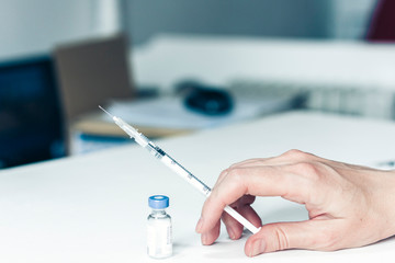 female hand with a medical syringe and bottle with insulin for diabetes on white table.