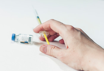 female hand with a medical syringe and bottle with insulin for diabetes on white table.