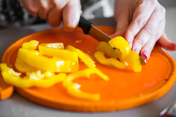 Frau in der küche schneidet gelbe Paprika für salat 