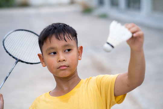 Asian kid boy playing badminton at home