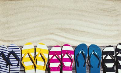 Naklejka premium Set of colorful flip flops on the beach deck