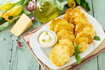 Vegan vegetable fritters zucchini and sour cream garlic sauce on the kitchen wooden table. Fried vegetarian cutlets or pancakes. The concept of fast food. Copy space.