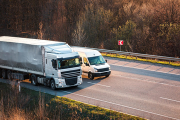 Arriving white truck on the road in a rural landscape at sunset