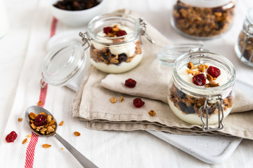 Crunchy honey granola in jars with flax seeds, cranberries, coconut, yogurt and cherry. Healthy, vegeterian fiber food. Breakfast time. Dieting concept for banner.