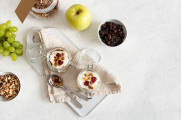 Homemade granola with nuts, fruits and yogurt in jars on white background. Healthy food, dieting. breakfast time. Copy space, top view