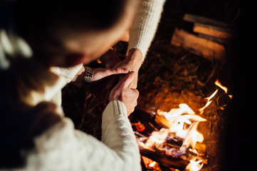  Holding hands a loving couple is standing over a fire at night