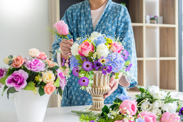 young women business owner florist making or Arranging Artificial flowers vest in her shop, craft and hand made concept