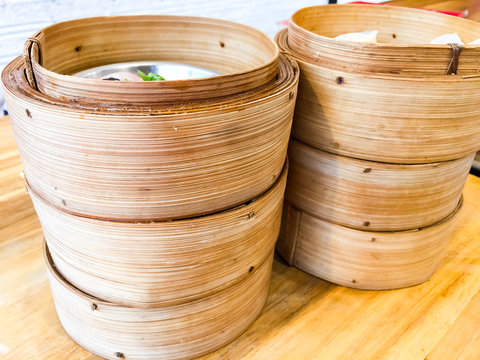 Dim sum , this is a popular Chinese food which were steamed. They are in the small bamboo basket. In the picture, there are six baskets in the wooden table which has food, pork wrapped in seaweed , sh