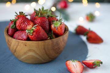 ripe strawberries in a wooden bowl on a white table