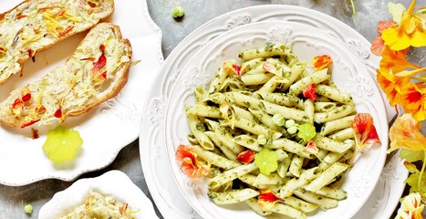different dishes with nasturtium - pasta with pesto of nasturtium leaves and butter with nasturtium flowers, sandwich (bruschetta) with nasturtium butter.
