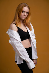 Stylish young girl with curly hair, smiling cutely, posing, on yellow background