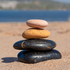 Fototapeta na wymiar Zen composition of pebbles on the sea sandy shore close up - summer holiday concept