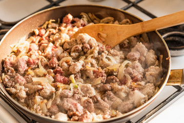 Cooking a stew of homemade sausages and mushrooms in a pan - traditional Italian mushroom sauce Boscaiola.