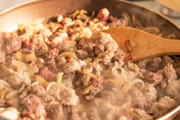 Cooking a stew of homemade sausages and mushrooms in a pan - traditional Italian mushroom sauce Boscaiola.