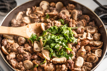 Cooking a stew of homemade sausages and mushrooms in a pan - traditional Italian mushroom sauce Boscaiola.