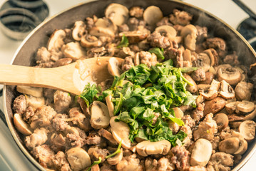Cooking a stew of homemade sausages and mushrooms in a pan - traditional Italian mushroom sauce Boscaiola.