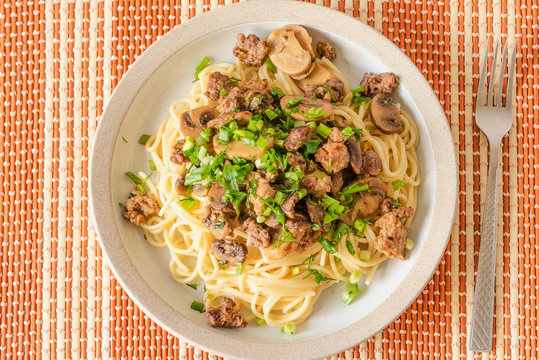 Spaghetti with homemade sausage and mushroom stew on a plate - traditional Italian pasta with Boscaiola mushroom sauce.