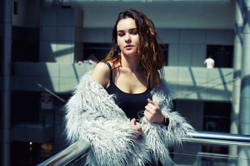 Portrait of a young fashionable woman in the city . The girl wears a dark t-shirt and a fur Cape