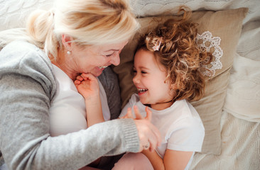 A top view portrait of small girl with grandmother having fun at home.