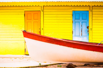 Beautiful bright colored wooden house on sea side with colorful wooden boat in front.
