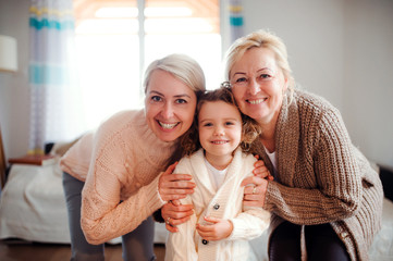 A portrait of small girl with mother and grandmother at home.