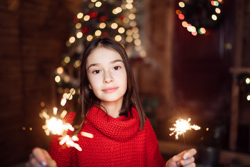 Portrait of a child girl looks with sparklers in their hands