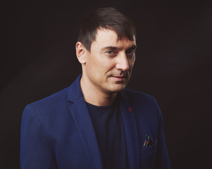 Obraz premium Portrait of handsome man wearing blue jacket, black background