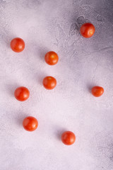 Bunch of cherry tomatoes on white textured stone concrete table, top view with copy space. Ingredients for cooking.