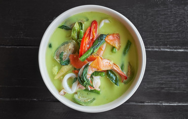 Thai food. Seafood green curry soup on dark wooden background