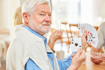 Senior Mann zeigt ein As beim Karten spielen
