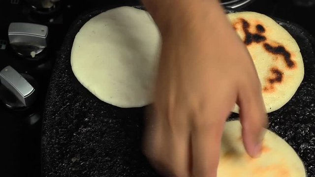 hands removing roasted arepa stove, traditional venezuelan food arepa preparation.