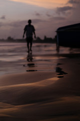 Fototapeta na wymiar silhouette of a man walking on the beach at sunset on the ocean