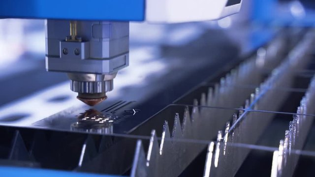 The industrial laser cutting torch cuts preparations from metal. Clip. Laser cutter in the production. Industrial cnc plasma cutting of metal plate. Closeup. lot of bright sparks.