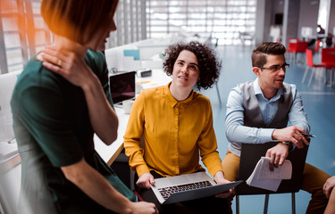 Group of young businesspeople working together in office, talking.