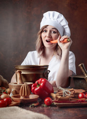 Young woman in a chef's uniform eating carrots.