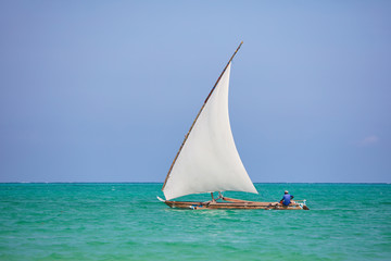 Sail boat with white sail and sitting sailor