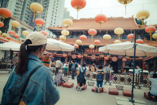 Girl pray at Wong Tai Sin Temple, New Kowloon in Hong Kong. Most famous Taoist temple exemplifies the architecture of a traditional Chinese temple.