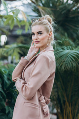 Beautiful fashion girl in green garden near plants. Beauty concept. Healthy organic lifestyle. Cover girl posing for fashion magazine in greenhouse