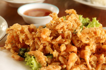 Close up fried small shrimp with sauce on wooden table in the restaurant, Thai food.