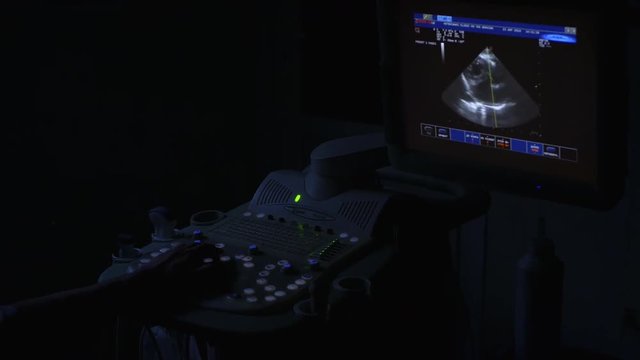 The doctor exemination patient with professional ultrasonography device in a dark room
