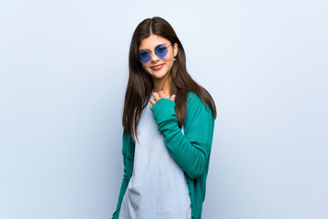 Teenager girl over blue wall with glasses and smiling