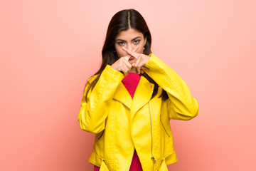 Teenager girl over pink wall showing a sign of silence gesture