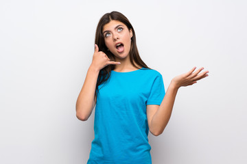 Teenager girl with blue shirt making phone gesture and doubting