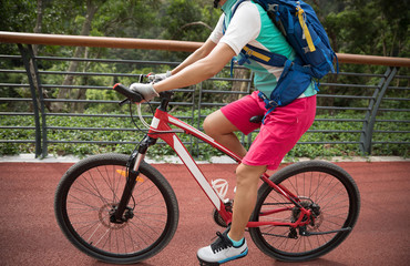 Woman cyclist riding Mountain Bike on forest trail